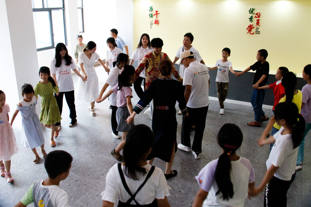 民族团结实践团成员同当地的小朋友一起拉歌跳民族舞蹈。.jpg